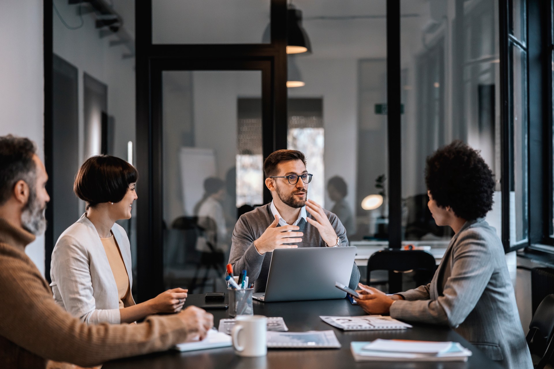 Ein engagierter Mentor erklärt den Mentees die Bedeutung des Projekts, während er in der Vorstandsetage eines Unternehmens sitzt.